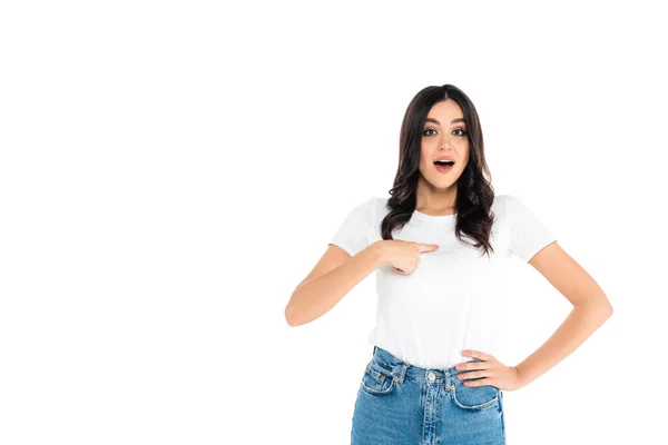 Surprised woman pointing with finger at herself while standing with hand on hip isolated on white - foto de stock