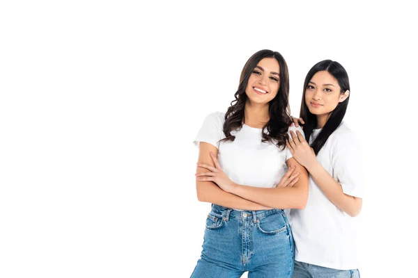 Happy young woman standing with crossed arms near asian friend isolated on white — Stockfoto