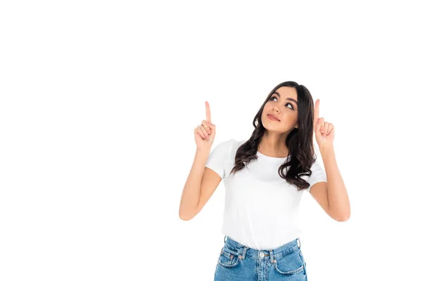 Smiling brunette woman looking up and pointing with fingers isolated on white — Stock Photo