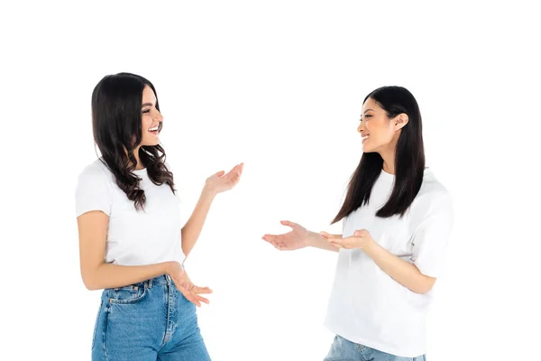 Веселі міжрасові жінки в футболках і джинсах розмовляють ізольовано на білому — стокове фото
