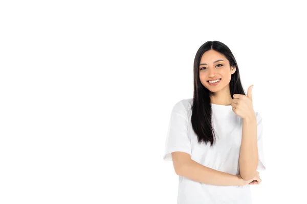 Giovane donna asiatica sorridente alla macchina fotografica e mostrando pollice su isolato su bianco — Foto stock