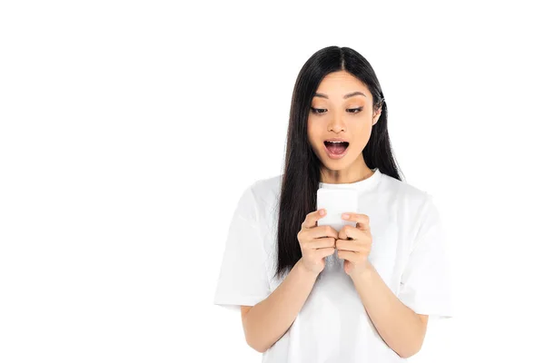 Stupito asiatico donna in t-shirt guardando cellulare isolato su bianco — Foto stock