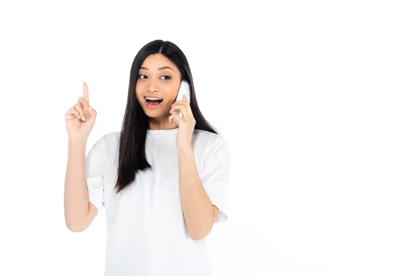 Asombrado asiático mujer mostrando idea gesto mientras hablando en móvil aislado en blanco - foto de stock