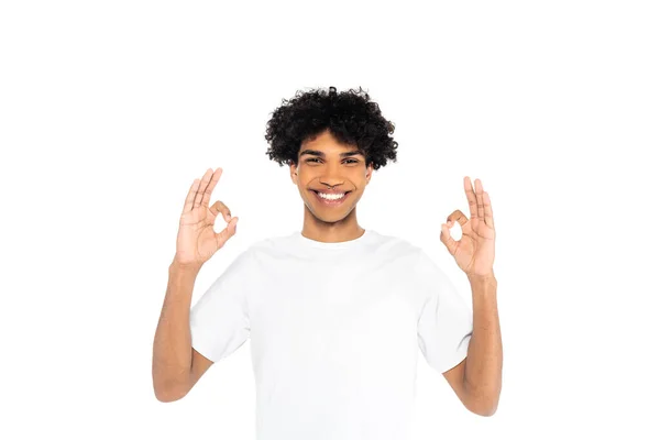 Homem americano africano alegre na t-shirt que mostra o gesto aprovado isolado no branco — Fotografia de Stock