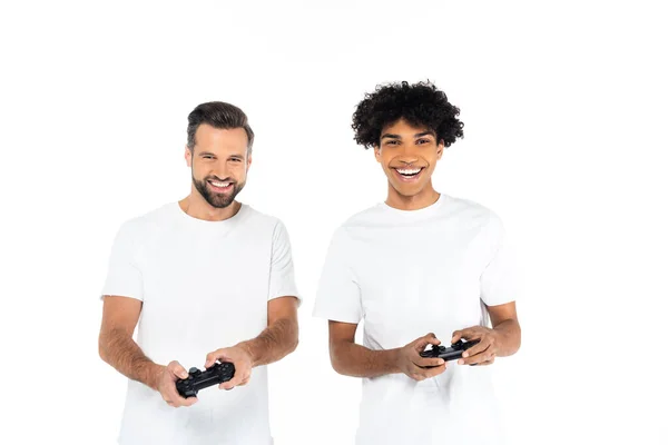 KYIV, UKRAINE - 5 DÉCEMBRE 2021 : heureux hommes interracial en t-shirts jouant avec des joysticks isolés sur blanc — Photo de stock