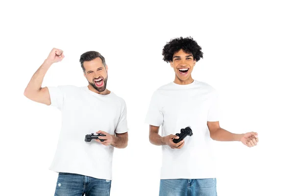 KYIV, UKRAINE - DECEMBER 5, 2021: joyful man shouting and showing win gesture while gaming with african american friend isolated on white — Stock Photo