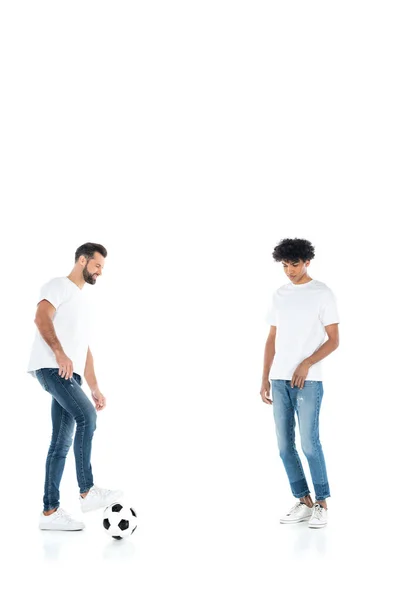 Vista completa del hombre sonriente jugando al fútbol con un amigo afroamericano en blanco - foto de stock