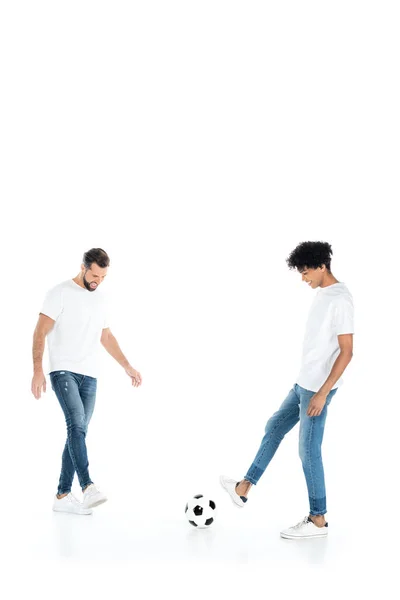 Vista completa de amigos interracial en jeans jugando fútbol sobre fondo blanco con espacio de copia - foto de stock