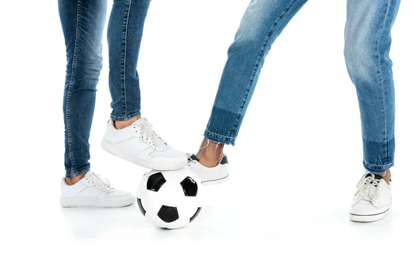 Cropped view of multiethnic friends in jeans and sneakers playing football on white — Fotografia de Stock