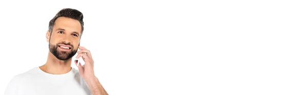 Бородатий чоловік посміхається під час розмови на мобільному телефоні ізольовано на білому, банер — стокове фото