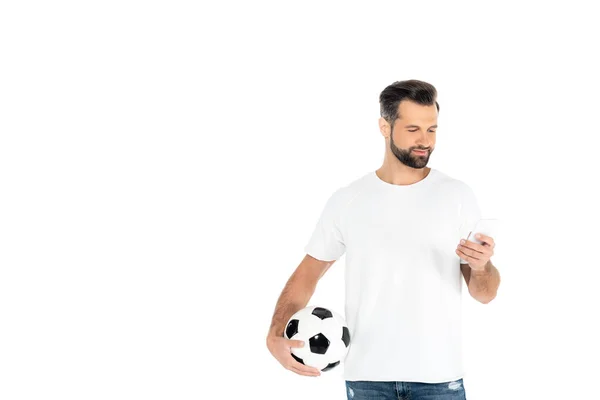 Positive man with soccer ball messaging on mobile phone isolated on white — Stockfoto