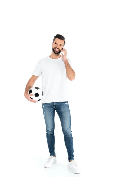 Vue pleine longueur de l'homme avec ballon de football parlant sur téléphone portable sur blanc — Photo de stock