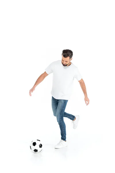 Full length view of man in t-shirt and jeans playing football isolated on white — стоковое фото