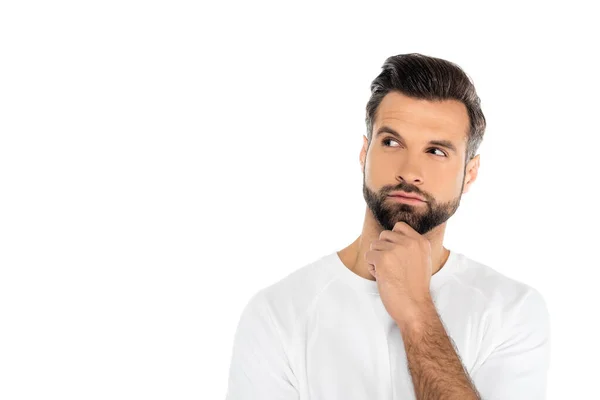 Thoughtful man in t-shirt holding hand near chin while looking away isolated on white — стоковое фото