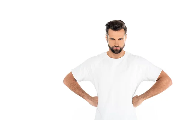 Angry man looking at camera while standing akimbo isolated on white — стоковое фото