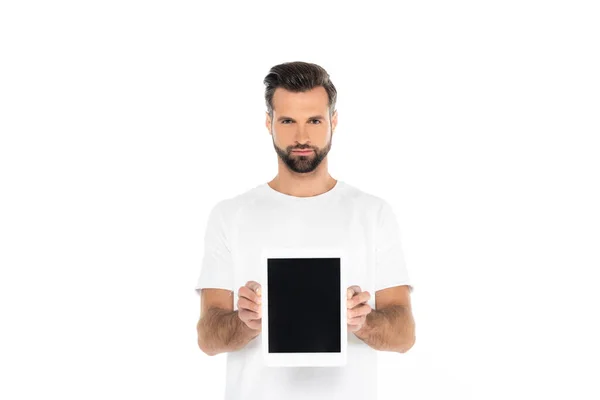 Bearded man holding digital tablet with blank screen while looking at camera isolated on white — стоковое фото