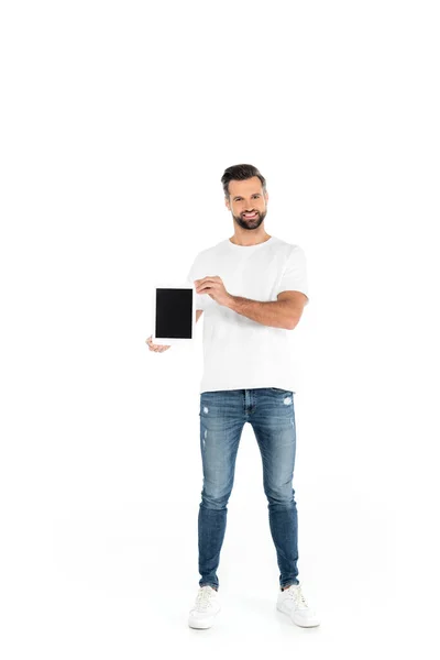 Visualizzazione a figura intera di uomo felice in jeans che mostra tablet digitale con schermo bianco su bianco — Foto stock