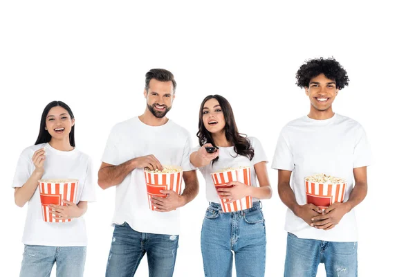 Junge Frau klickt Fernsehkanäle in der Nähe von glücklichen multiethnischen Freunden Popcorn essen isoliert auf weiß — Stockfoto