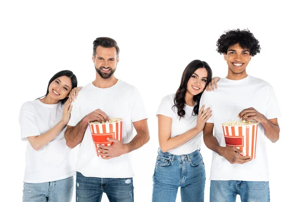 Fröhliche multiethnische Männer mit Popcorn-Eimern sehen Film mit zufriedenen Frauen isoliert auf weiß — Stockfoto