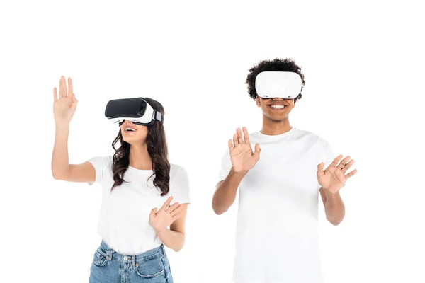 Cheerful interracial friends gesturing while gaming in vr headsets isolated on white — Stock Photo