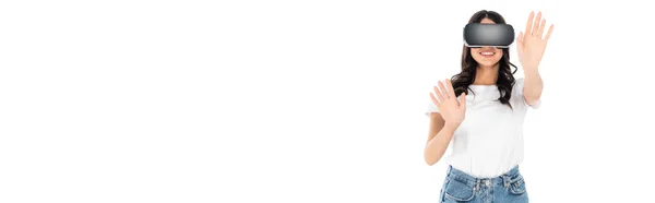 Femme brune gaie en réalité virtuelle casque toucher quelque chose tout en jouant isolé sur blanc, bannière — Photo de stock