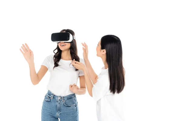 Alegre mulher jogos no vr fone de ouvido perto asiático amigo isolado no branco — Fotografia de Stock