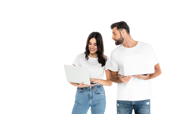 Sonriente mujer usando portátil cerca curioso hombre aislado en blanco - foto de stock