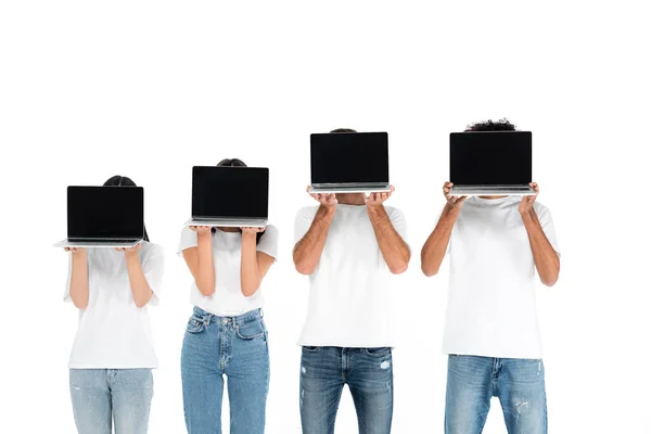 Multicultural friends in jeans and t-shirts obscuring faces with laptops with blank screen isolated on white — Photo de stock