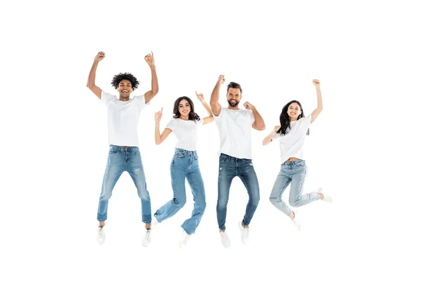 Amigos multiétnicos animados em jeans olhando para a câmera enquanto levita no branco — Fotografia de Stock