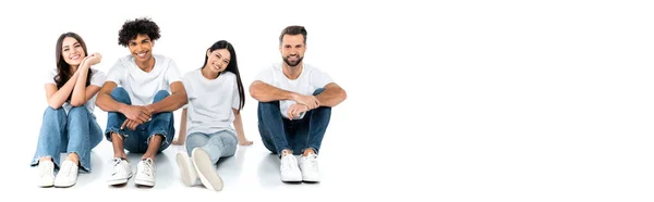 Homens e mulheres multiculturais felizes em jeans sentados e olhando para a câmera em branco, banner — Fotografia de Stock