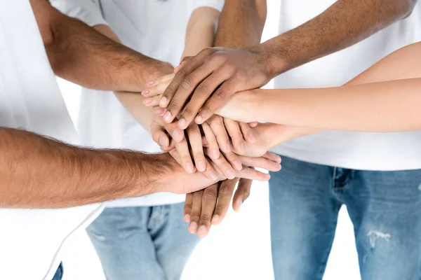 Partial view of multiethnic friends in jeans joining hands isolated on white — стоковое фото