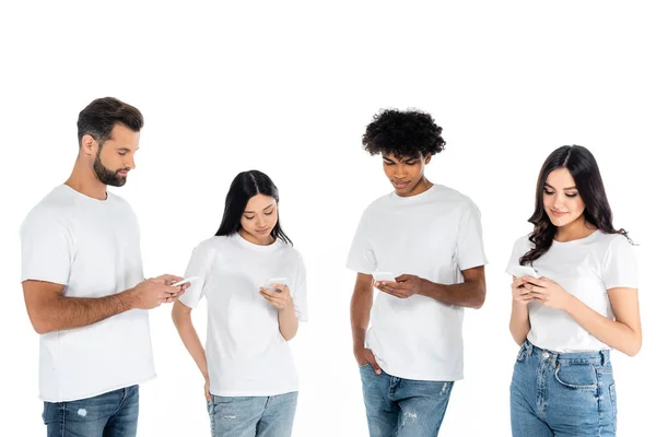 Positive interracial friends in t-shirts messaging on mobile phones isolated on white — Stock Photo