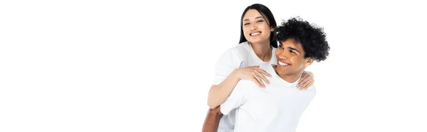 Feliz africano americano homem piggybacking animado asiático mulher isolado no branco, banner — Fotografia de Stock