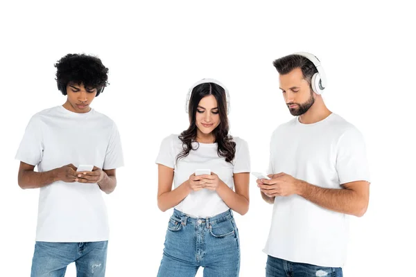 Amigos multiculturales en auriculares usando teléfonos móviles aislados en blanco - foto de stock