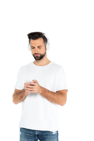 Man in t-shirt and headphones using mobile phone isolated on white — Fotografia de Stock