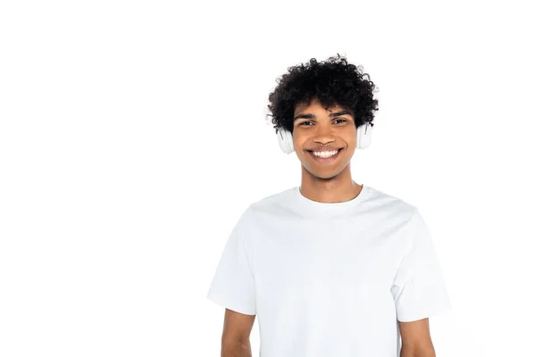 Encaracolado homem americano africano em fones de ouvido sorrindo para a câmera isolada em branco — Fotografia de Stock