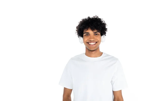 Curly african american man in headphones smiling at camera isolated on white — Foto stock