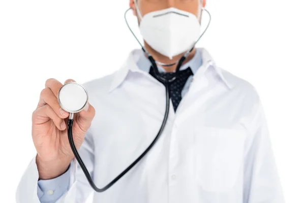 Visão parcial do médico desfocado em máscara médica segurando estetoscópio isolado no branco — Fotografia de Stock