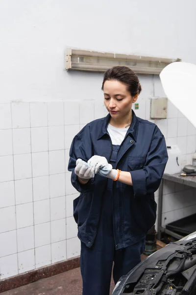 Mechanic wearing gloves near car in garage — Fotografia de Stock