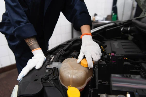 Cropped view of mechanic in gloves unscrewing cap in car in service — Stock Photo