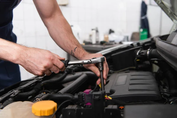 Обрізаний вид механіка за допомогою ключа під час роботи з авто в гаражі — стокове фото