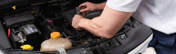 Cropped view of mechanic working with auto in service, banner — стоковое фото