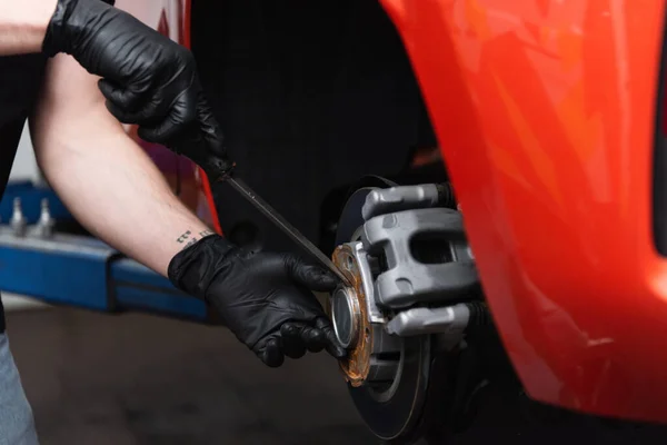 Cropped view of mechanic in gloves working with wheel brake disk in car service — Stock Photo