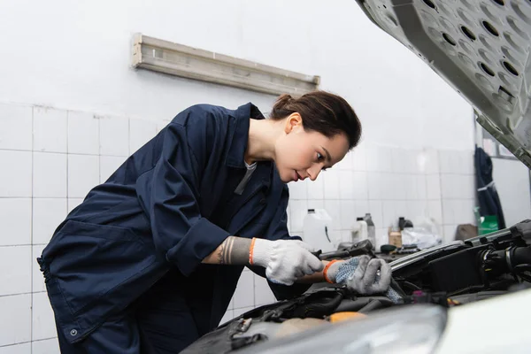 Tattooed mechanic using wrench while working with auto in service — Stockfoto