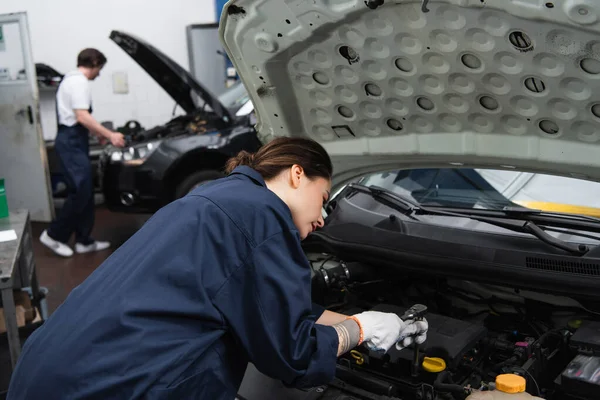 Forewoman working with car engine in garage — Stock Photo
