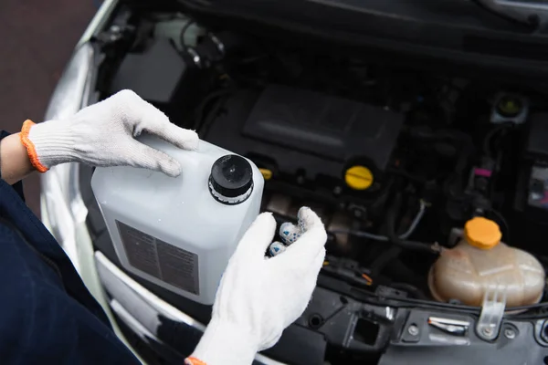Cropped view of mechanic holding canister near blurred car — Stockfoto