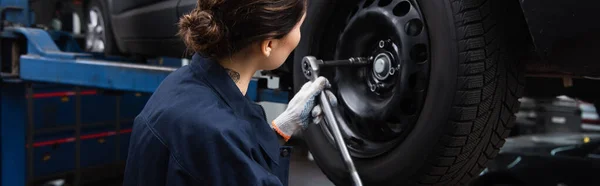 Workwoman en gant de travail avec roue de voiture et clé dans le garage, bannière — Photo de stock