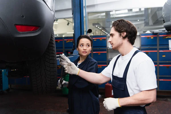 Young mechanics working with car wheel in service — Stock Photo