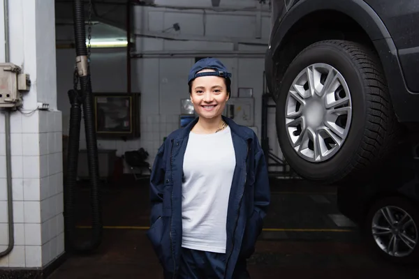 Smiling mechanic looking at camera near car in garage — Stock Photo