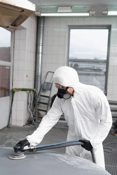 Foreman in protective suit polishing auto in garage — Stock Photo